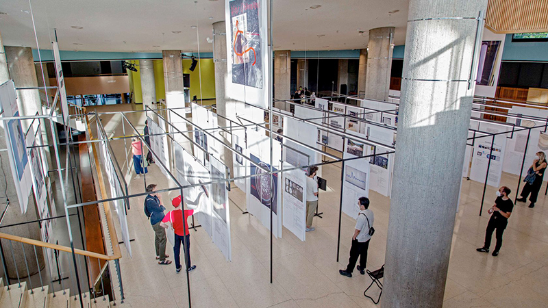 Large prints on paper hanging on metal scaffolding in the foyer of a museum