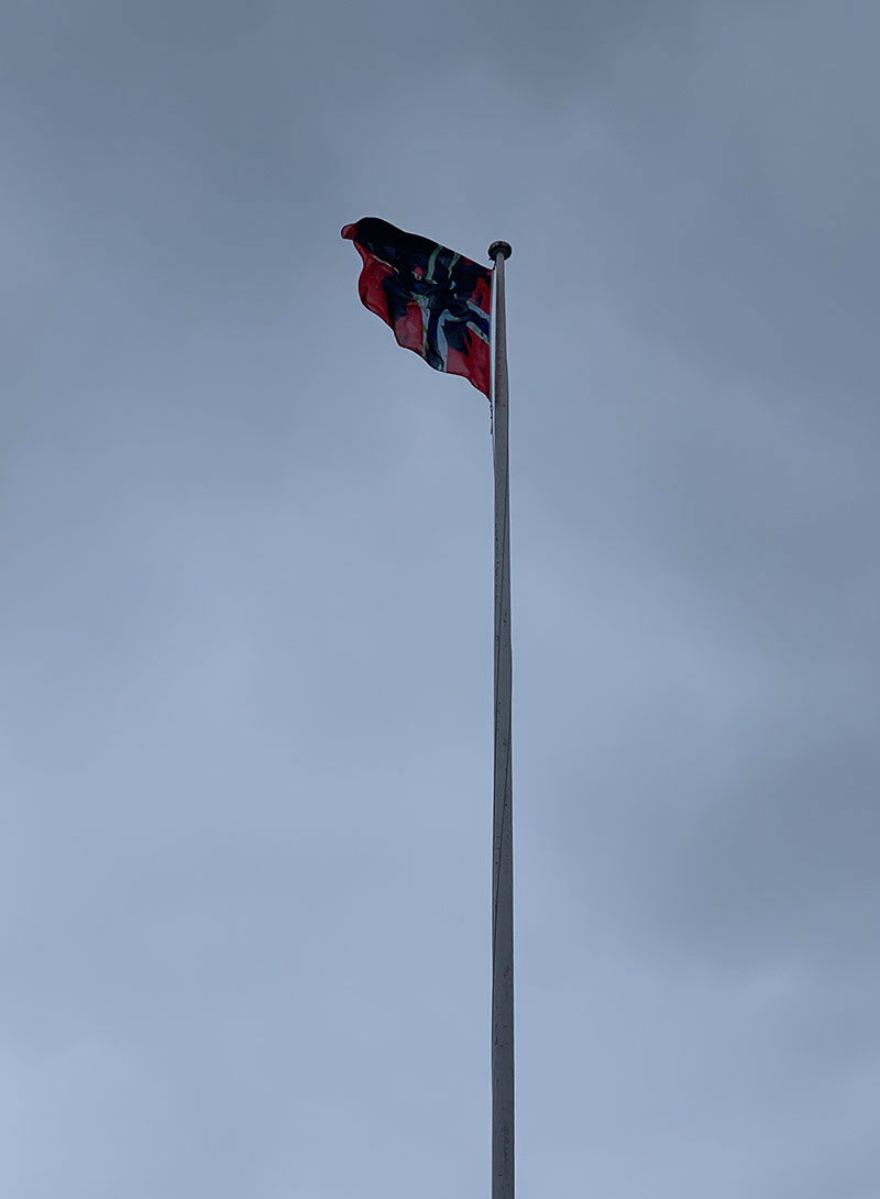 a flag of Norway blackened with oil blowing in the wind