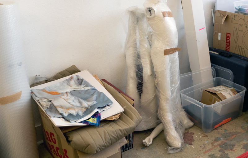 a wrapped up headless mannequin beside moving box