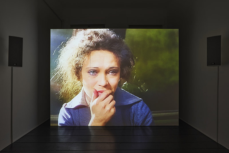 A video installation in a gallery featuring one projection with a close up of a crying woman