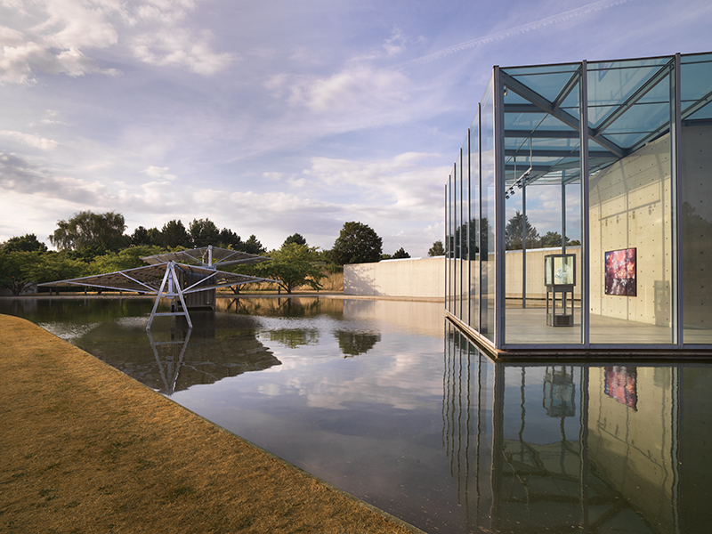 A  glass entrance to a museum built atop a serene pond