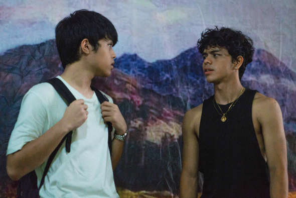 Two young men staring at each other in front of mountain backdrop