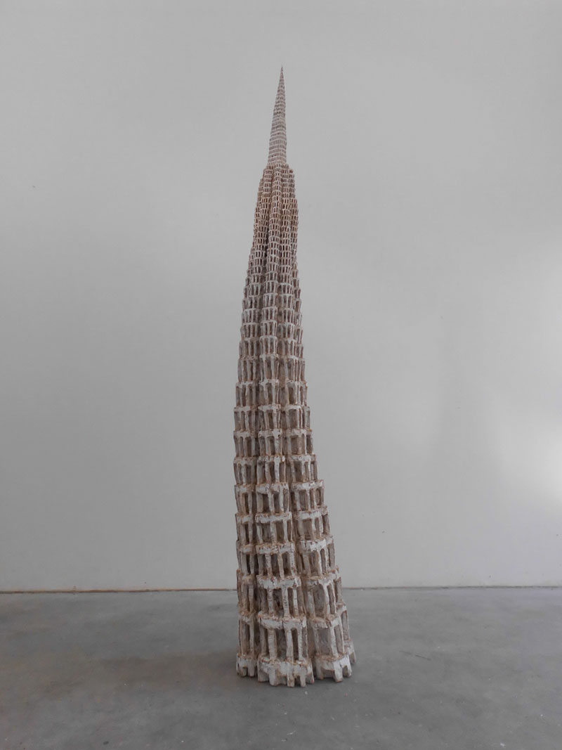 a sculpture depicting a tower with many small windows, like honeycomb, made out of wood