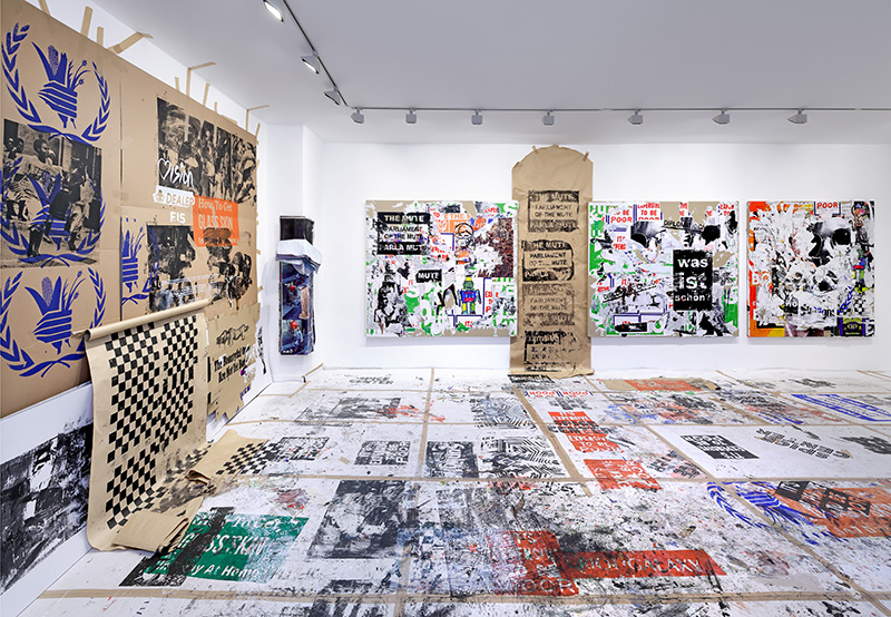 A gallery installation view of posters taken off the streets and plastered on the walls and floor