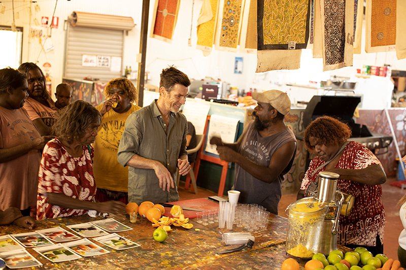 A group of people in what looks like an artist's workshop standing behind a large table