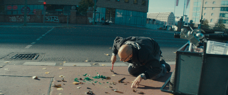 A man breaks glass with a hammer on a bike path