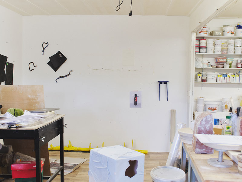 A white studio space with small ceramic sculptures hung on the wall