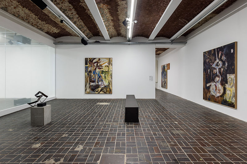 a photo of a gallery room with paintings hung on the walls