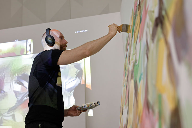 A man wearing headphones and painting