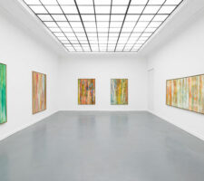 Four large abstract paintings hanging in a gallery with a skylight
