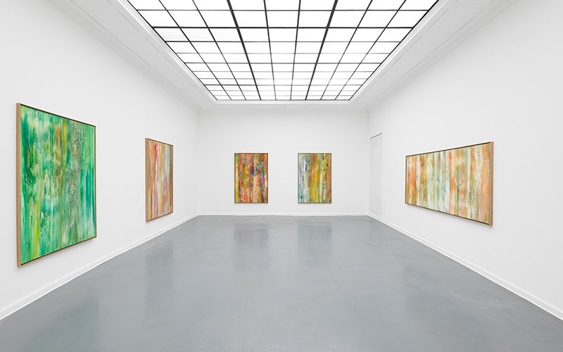 Four large abstract paintings hanging in a gallery with a skylight