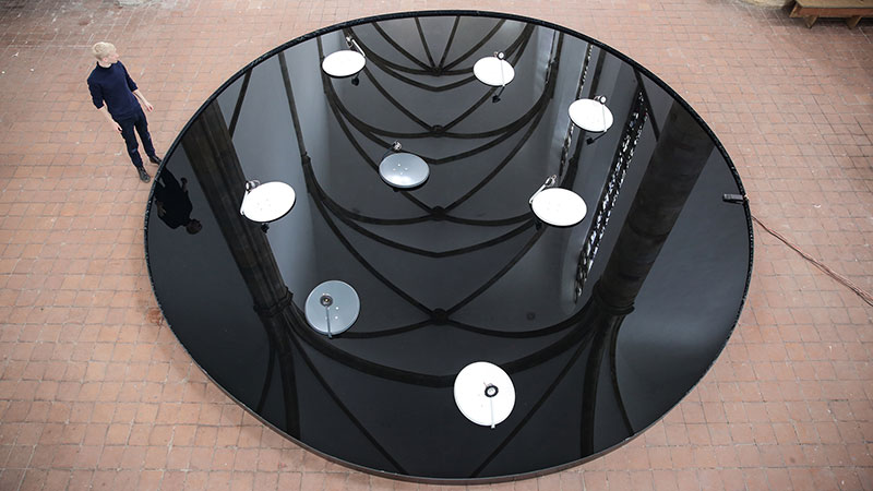 A circular artificial pond built in a gallery with discs floating in it, seen from above