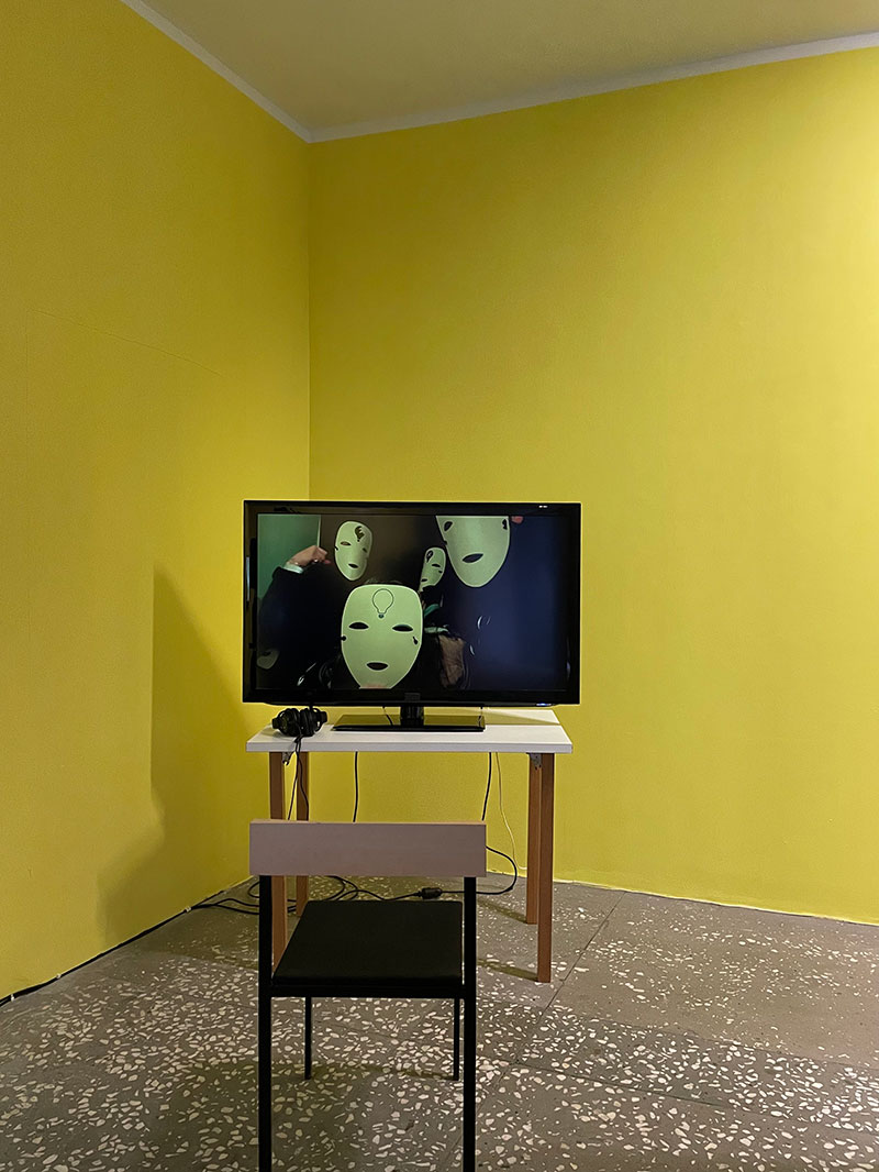 a small table with a monitor on it and a chair in front of it in a yellow room