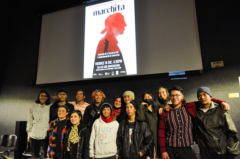 Photo of a group of young people standing in front of a film projection screen