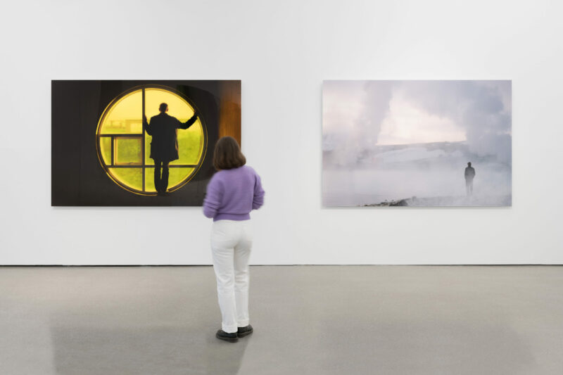 a person looking at two photographs on the wall in an exhibition space