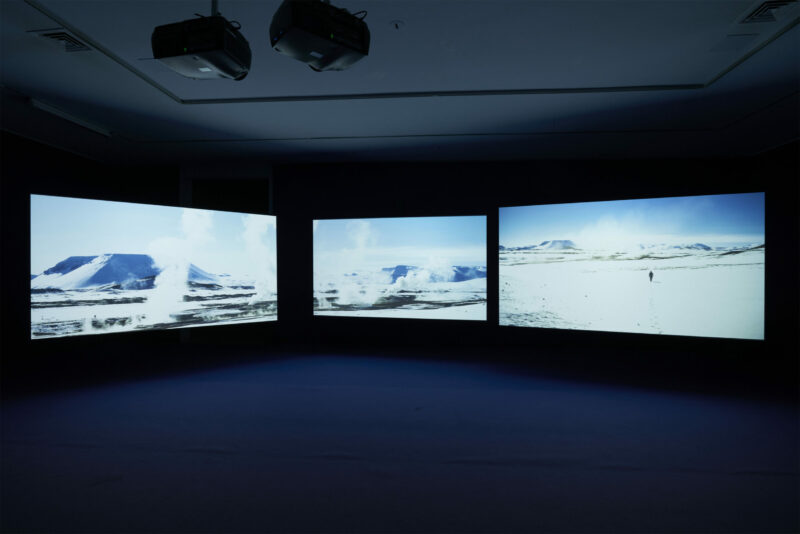 three screens in a screening room showing a landscape