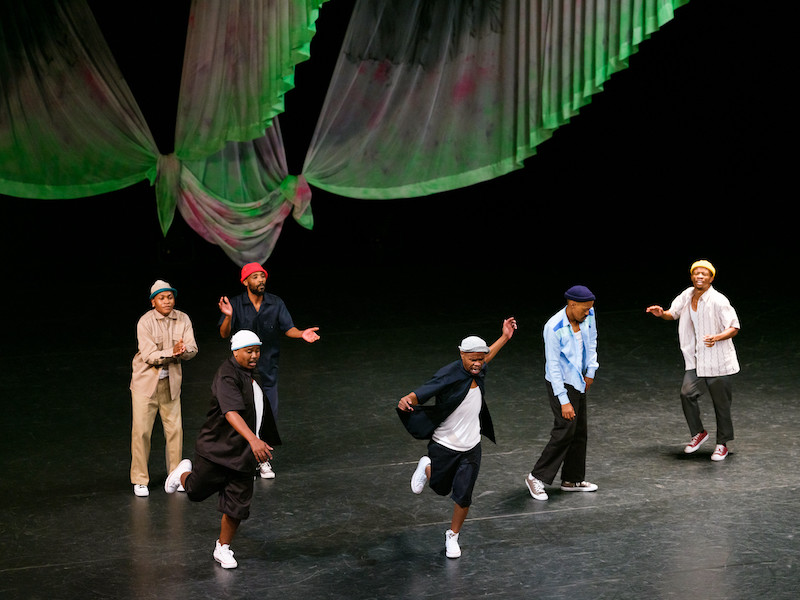 Six men dancing the pantsula and clapping